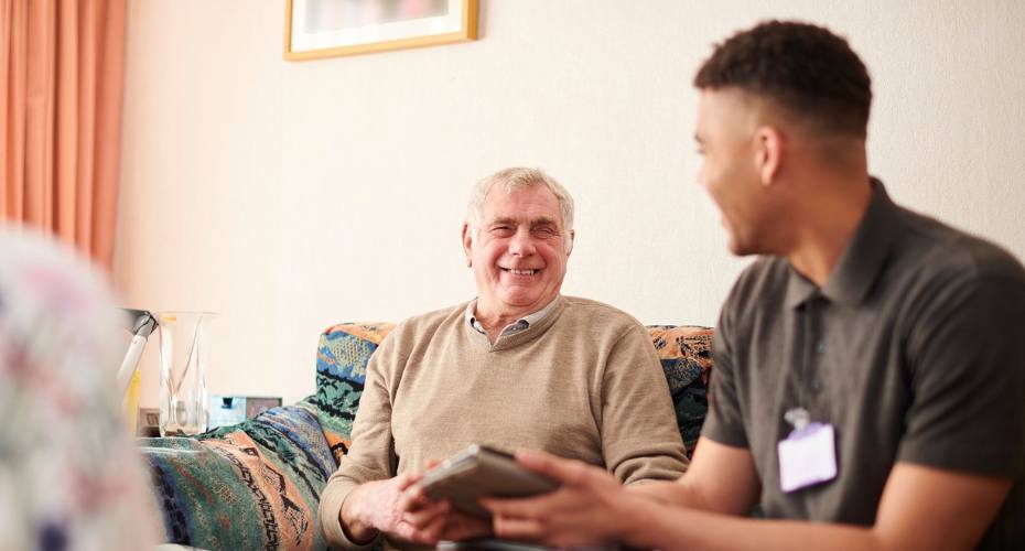 Trusted Assessor Level 1 - Man sat on sofa listening to advice.