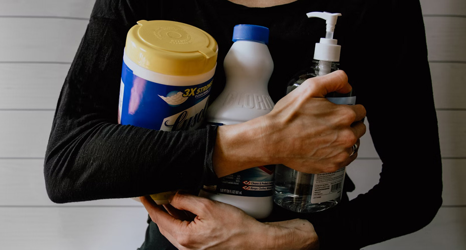 An image of a woman holding cleaning products