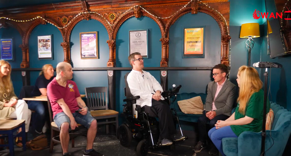 An image of a man in a powered chair sitting amongst a group of people on a TV show