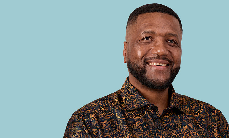 image of a man wearing a patterned shirt smiling to camera