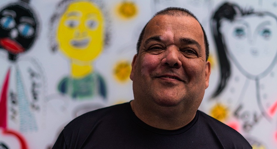 A man smiling in front of a background with animated faces