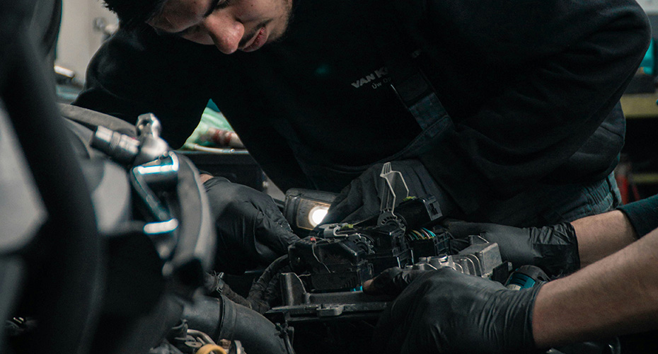 An image of a mechanic working on a car engine bay