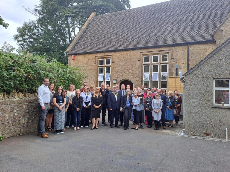 Photo of approximately twenty people stood in front of a traditional stone building