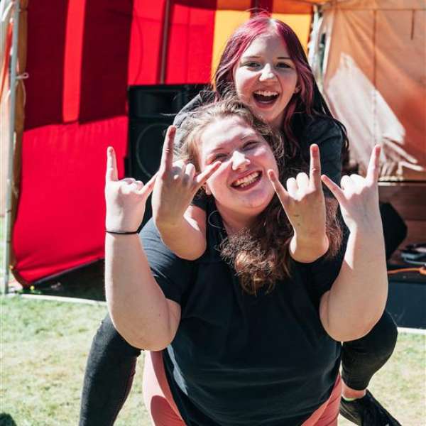 Two people smiling, with one giving the other a piggyback.