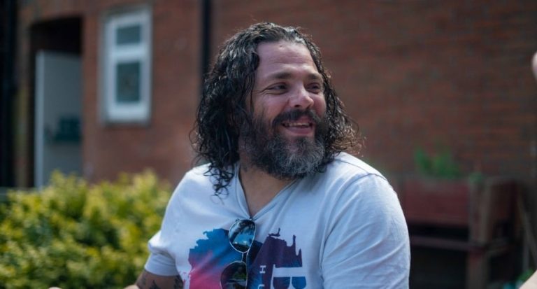 Man with long hair and beard smiling.