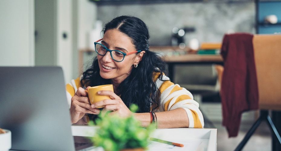 Woman sat with coffee looking at laptop