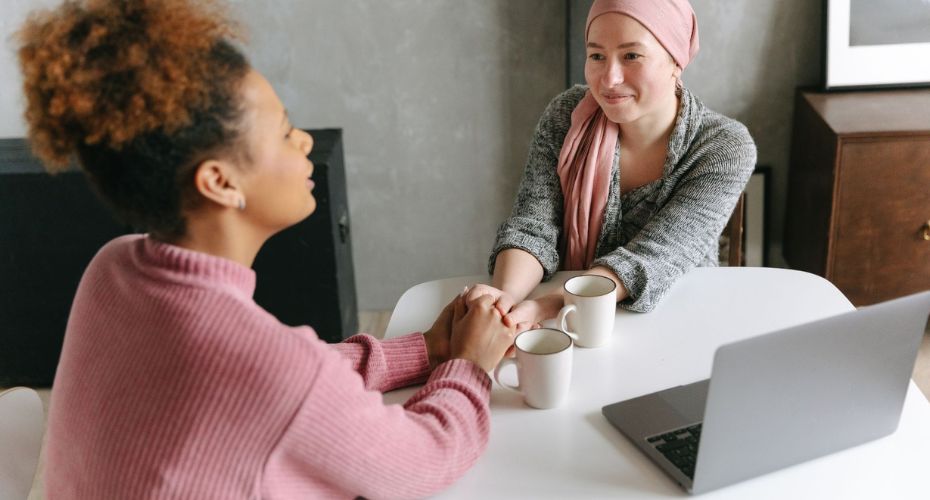 Trusted Assessor Level 4 - Two women sat at a table with coffee and a laptop