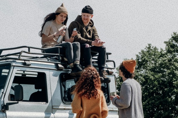 Group of young people sat on the roof of a car