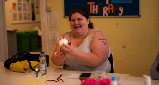 Woman sat at a table wearing a grey top
