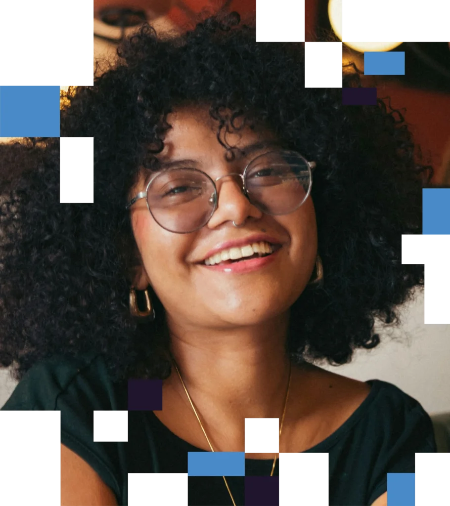 An image of a young woman with curly hair and glasses smiling